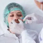 Doctor performing nasal surgery on female