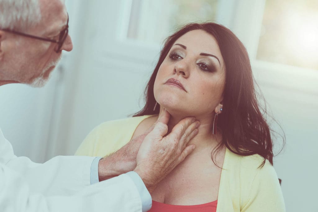 Doctor doing thyroid exam on female patient